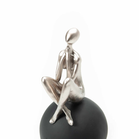 Figure Sitting on Black Ball